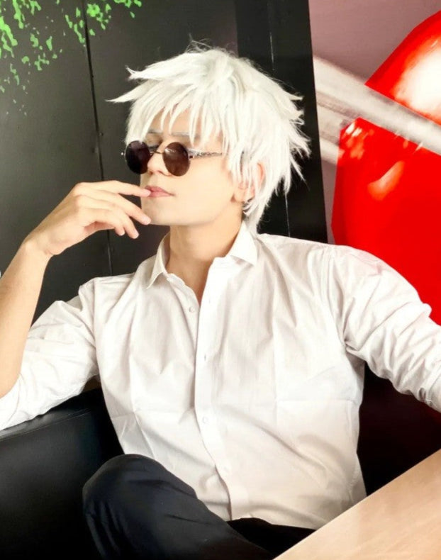 Person with white hair and sunglasses sitting against a colorful background